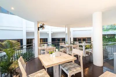 a restaurant with tables and chairs on a balcony at Bali Karma Sajtra Hotel in Seminyak