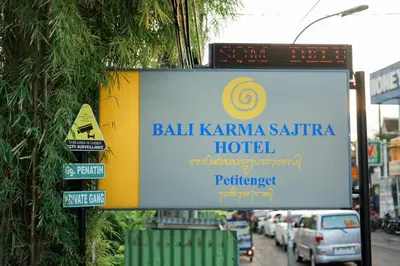 a sign for a hotel on the side of a street at Bali Karma Sajtra Hotel in Seminyak
