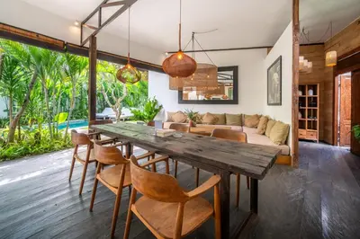 an open living room with a wooden table and chairs at Villa Hatari Canggu in Kerobokan