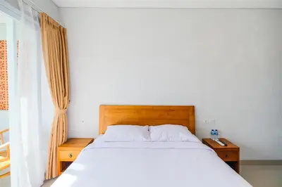 a bedroom with a white bed and a window at Dharma Guest House Seminyak RedPartner in Seminyak