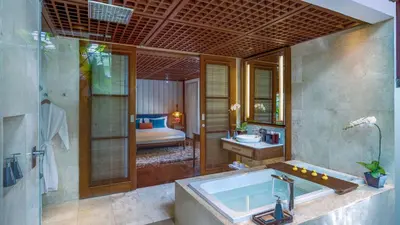 a bathroom with a tub and a bedroom with a bed at Villa Windu Sari in Seminyak