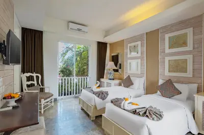 a hotel room with two beds and a balcony at The Kanjeng Suites Petitenget in Seminyak