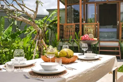 a table with a bowl of fruit and wine glasses at Villa Kamal Umalas in Kerobokan