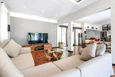 a living room with two white couches and a tv at Anedda Merta Sari Villa Sanur in Sanur
