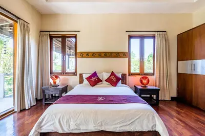 a bedroom with a large bed and windows at Anedda Merta Sari Villa Sanur in Sanur