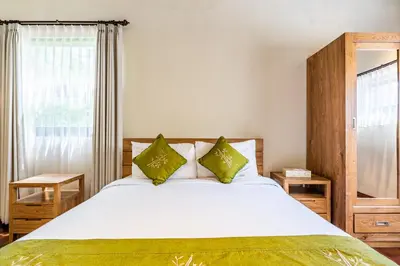 a bedroom with a large white bed with green pillows at Anedda Merta Sari Villa Sanur in Sanur