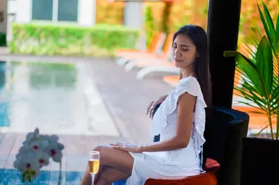 a woman sitting in a chair with a glass of wine at Bali Yarra Villas - Seminyak in Seminyak