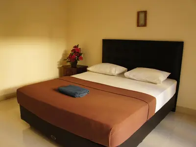 a bedroom with a large bed with a black headboard at Waringin Homestay in Kuta