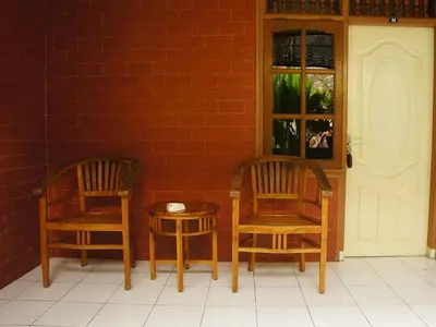 two chairs and a table next to a brick wall at Waringin Homestay in Kuta