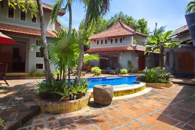a house with a swimming pool and palm trees at Villa Naga Maya in Legian