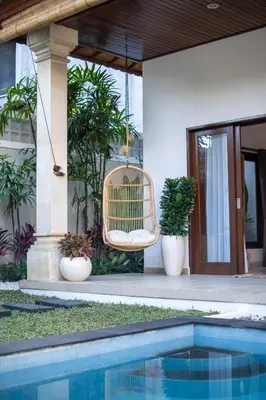 a house with a rattan chair and a swimming pool at CASA MALEH 2BR lively villa in kayuaya seminyak in Seminyak