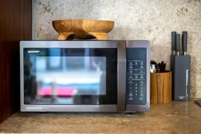 a microwave oven sitting on a counter with a wooden block at CASA MALEH 2BR lively villa in kayuaya seminyak in Seminyak