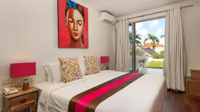 a bedroom with a bed with a painting on the wall at Casa Mateo Villa in Seminyak