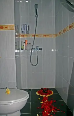a bathroom with a toilet and a shower with flowers on the floor at Manggar Indonesia Hotel in Kuta