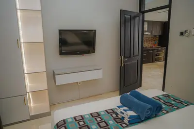 a room with a tv on the wall and a chair at 4 BEDROOM VILLA KUTA REGENCY B10 in Kuta