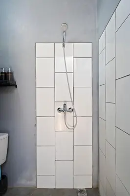 a shower in a bathroom with white tiles at Jaci Residence by Betterplace in Canggu