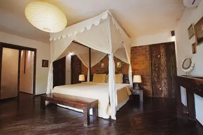 a bedroom with a canopy bed and a bench at Phinisi Villas - Seminyak Beach in Seminyak