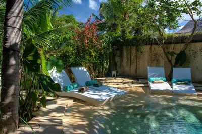 a group of chairs sitting next to a swimming pool at Phinisi Villas - Seminyak Beach in Seminyak