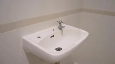 a white sink in a white tiled bathroom at Pondok Mirah in Kuta