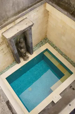 a swimming pool with a table and a fountain at Pondok Mirah in Kuta