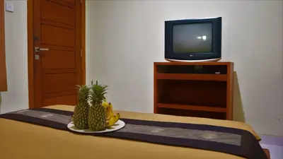 a room with a television and a plate of pineapple at Pondok Mirah in Kuta