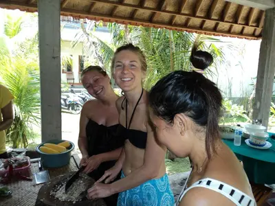 three women in bathing suits standing around a cake at Puri Clinton Bali in Nusa Dua