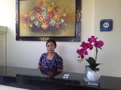 a woman sitting on a table in front of a painting at Puri Clinton Bali in Nusa Dua
