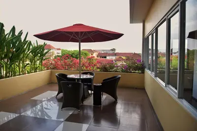 a table with chairs and an umbrella on a balcony at The Kana Kuta Hotel in Kuta