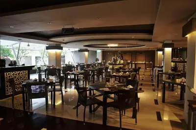 a dining room with tables and chairs in a restaurant at The Kana Kuta Hotel in Kuta