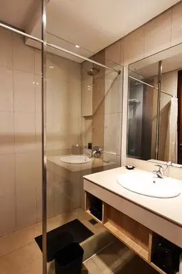 a bathroom with a sink and a shower at The Kana Kuta Hotel in Kuta