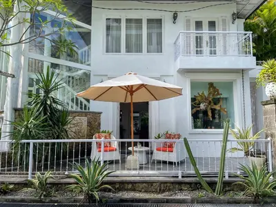 a white house with an umbrella and chairs at Beach House Canggu - 150m Berawa beach in Canggu