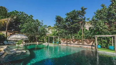 a pool at a resort with an umbrella and chairs at Amnaya Resort Nusa Dua in Nusa Dua