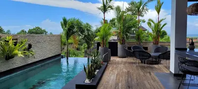 a pool with chairs and palm trees on a building at Villa Mimpi Bali in Jimbaran