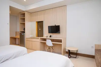 a bedroom with a bed and a desk with a television at Lega Legi Town House Seminyak by The Lavana in Seminyak