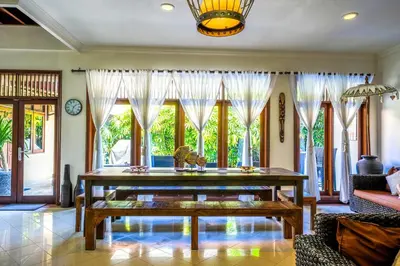 a living room with a wooden table and windows at Villa SANKET - KUTA - 6 bedrooms - 6 bathrooms - Great Location in Kuta