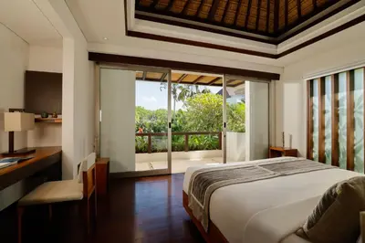 a bedroom with a bed and a desk and a window at Jimbaran Bay Villas by Nakula in Jimbaran