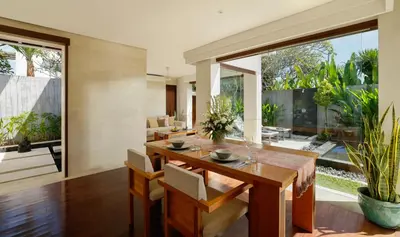 a dining room with a wooden table and chairs at Jimbaran Bay Villas by Nakula in Jimbaran