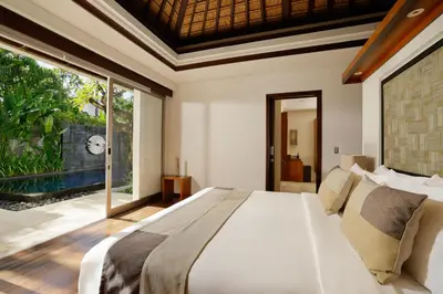 a bedroom with a large bed and a large window at Jimbaran Bay Villas by Nakula in Jimbaran