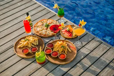 a table with plates of food and drinks next to a pool at J4 Hotels Legian in Legian