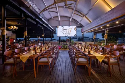 a restaurant with wooden tables and chairs and a large screen at J4 Hotels Legian in Legian