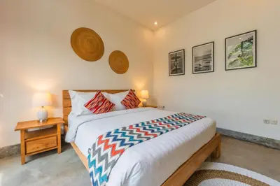 a bedroom with a bed and a nightstand with two lamps at Canggu Escape Villa By Island Escape in Canggu