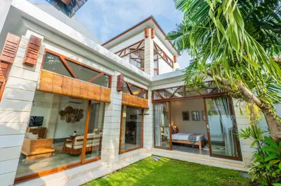 a house with large windows and a bedroom at Canggu Escape Villa By Island Escape in Canggu