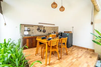 a kitchen with a wooden table and chairs at Kamaratih Villas by Maheswara in Legian