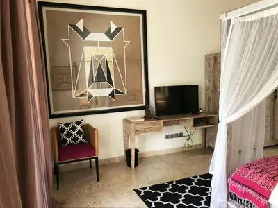 a bedroom with a bed and a tv and a chair at villa LA PLAYA in Seminyak