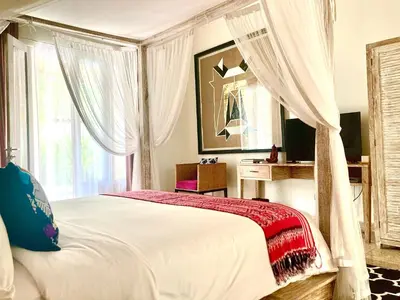 a bedroom with a bed with a canopy and a desk at villa LA PLAYA in Seminyak