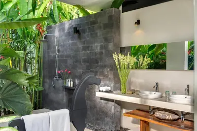 a bathroom with a stone wall with plants at Villa Kavya - 8-minute walk from Berawa Beach in Canggu