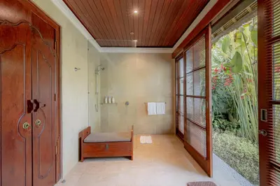 a bathroom with a shower and a bench next to a door at Villa Dorado - Steps from Jimbaran Beach in Jimbaran