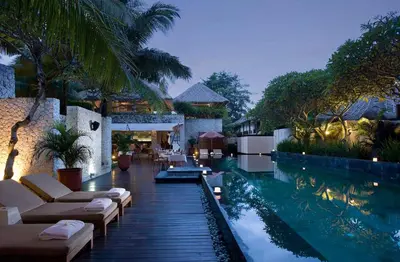 a swimming pool with lounge chairs and a resort at Villa Dorado - Steps from Jimbaran Beach in Jimbaran