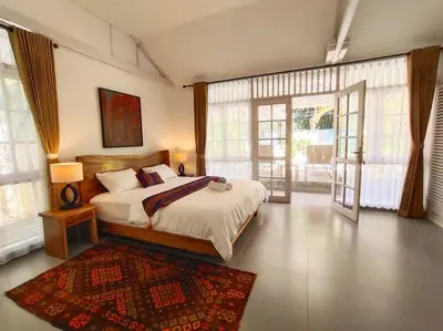 a bedroom with a bed and a large window at Miracle Villa Sanur in Sanur