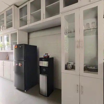 a kitchen with a black refrigerator and white cabinets at Miracle Villa Sanur in Sanur